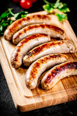 Grilled sausages on a wooden cutting board with parsley and tomatoes.