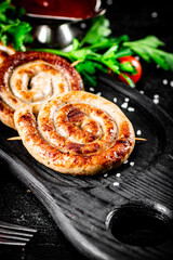Round grilled sausages on a tray with tomato sauce.