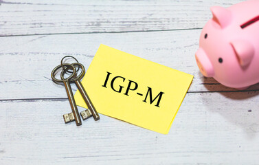 A sigla IGP-M escrita em um pedaço de papel. Chaves de uma casa e um cofrinho na composição....