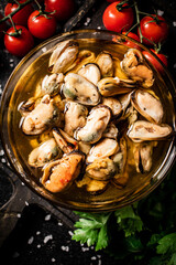 Pickled mussels in a bowl on a cutting board with cherry tomatoes. 