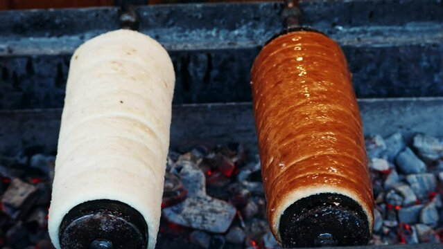 Preparation of the Hungarian and Romanian traditional Christmas bread, chimney cake, kurtos kalacs trdelnik roasted over charcoal in market. German and Hungarian sweet specialty made in Budapest.
