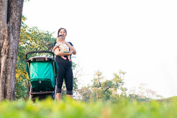 Asian mom use stroller kid boy recreation in outdoor public park