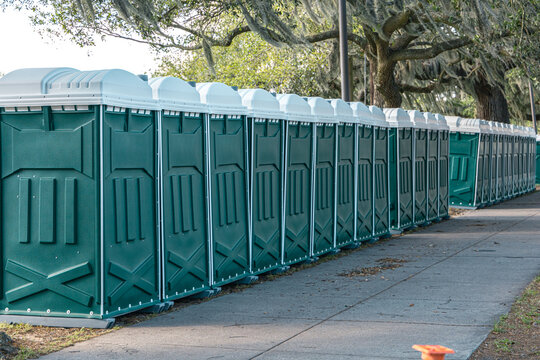 Row of green porta portable potty outhouses ready for use at a concert, festival, or event