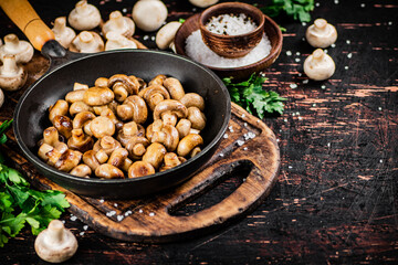 Frying pan with fried small mushrooms with parsley. 