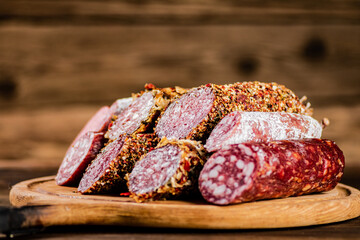 Different types of salami sausage on a wooden cutting board. 