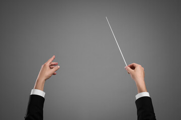 Professional conductor with baton on grey background, closeup