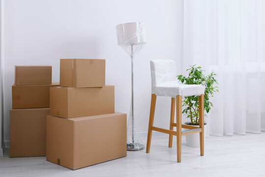 Boxes, lamp and chair wrapped in stretch film indoors