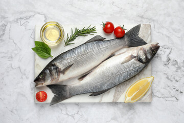 Sea bass fish and ingredients on white marble table, top view
