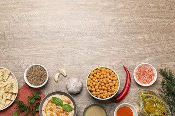 Many different ingredients on wooden table, flat lay with space for text. Cooking delicious hummus
