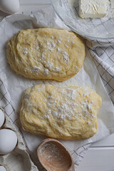 Dough, eggs and flour on white wooden table, flat lay. Cooking ciabatta
