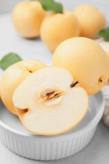 Naklejka na ściany i meble Bowl with delicious apple pears on white table, closeup