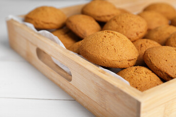 Delicious oatmeal cookies in tray on white wooden table, closeup