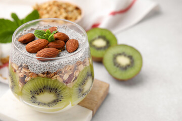 Delicious dessert with kiwi, chia seeds and almonds on light table, closeup. Space for text