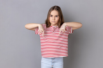 Here and right now. Portrait of serious bossy dark haired little girl wearing striped T-shirt...