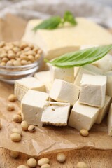 Delicious tofu cheese, basil and soybeans on wooden board, closeup
