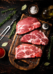 Raw pork steak on a wooden cutting board with tomato sauce,rosemary and spices. 