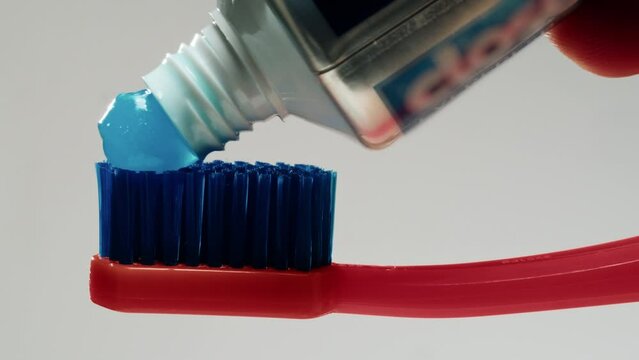 Blue toothpaste applying on brush against white background, morning, medical tooth paste.