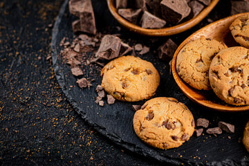 Cookies with pieces of milk chocolate on a stone board. 