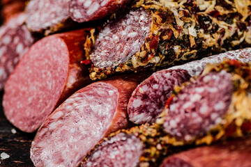 Slices of various salami in a pile on the table. 