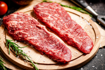 Raw steak on a wooden cutting board. 