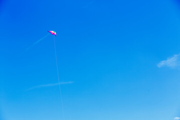 Colorful rainbow traditional classic kite with contrail cloud and blue sky in minimalistic landscape