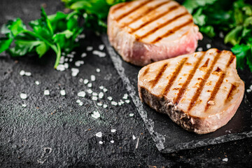 Grilled tuna on a stone board with parsley and salt. 