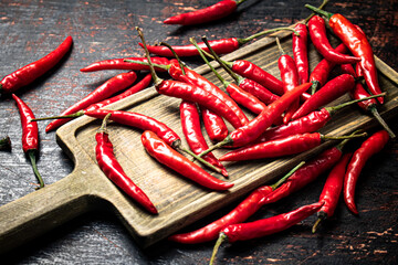 Red chili pepper pods on a cutting board.