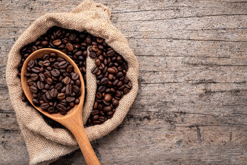Background of dark roasted coffee beans with scoops setup on wooden background with copy space.