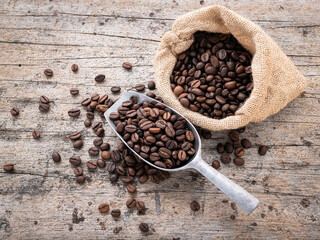Background of dark roasted coffee beans with scoops setup on wooden background with copy space.