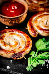 Grilled sausages on a stone board with tomato sauce and parsley. 