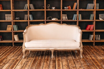 White retro sofa standing in the living room with stylish interior design and collections of books...