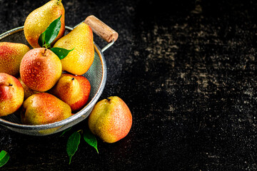 Juicy pears in a colander with foliage.