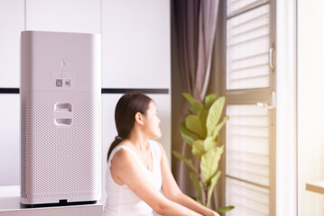 Air purifier white colour modern style in a living room for refresh air flow with blur happy woman at home,Advanced air purifying and protect Pm2.5