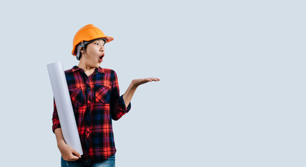 Young female engineer wearing a yellow safety helmet with Blueprints