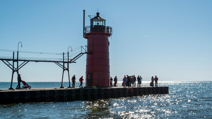 The late afternoon sun creates silhouettes of a group of visitors to the South Haven lighthouse on Lake Michigan. 