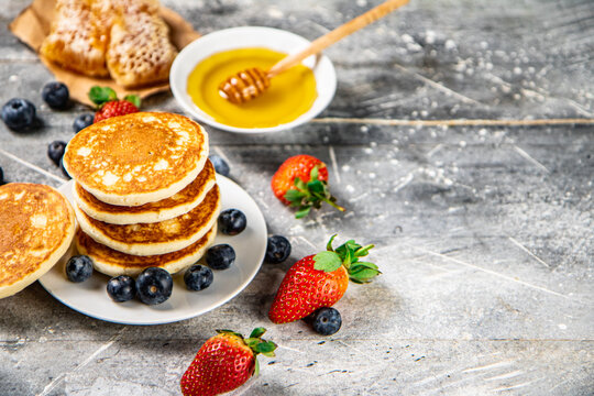 Pancakes in a plate with berries and honey. 