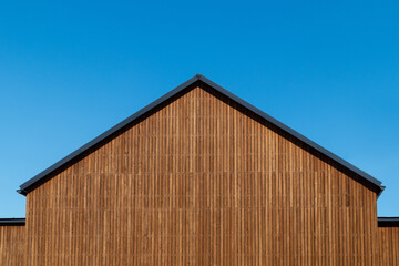 Facade decoration of the roof gable with natural wood plank of a new modern house, copy space.