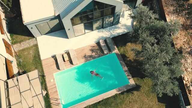 Aerial view of luxury pool villa and woman swimming at the pool.