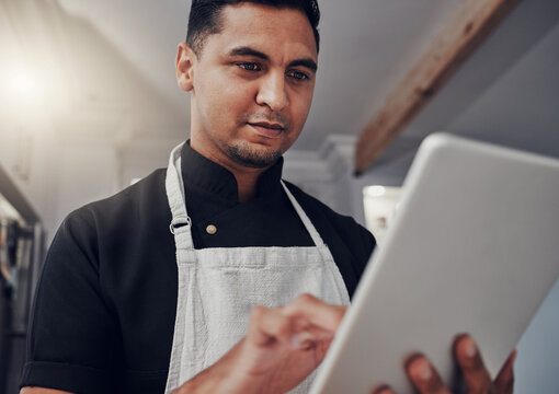 Man With Apron, Focus And Tablet For Online Recipe, Cooking Instructions And Connection In Kitchen. Male, Chef And Gentleman With Device, Communication And Search For Ingredients, Thinking And Ideas