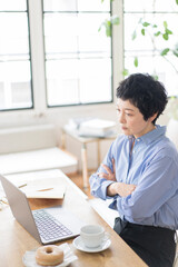 ノートパソコンを使ってテレビ電話で画面越しの相手と話をするアジア人女性、ミドル世代