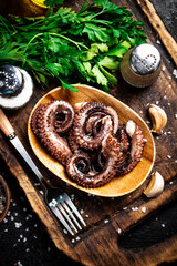 Fresh octopus on a plate on a cutting board with herbs and spices.