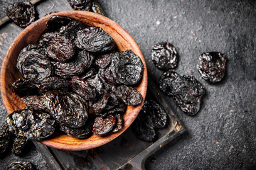 Prunes in a plate on a cutting board. 