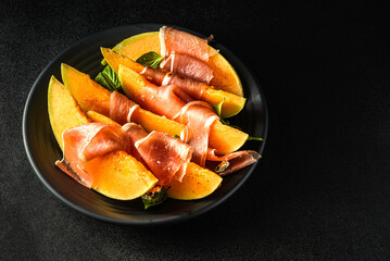 melon with parma on a dark background