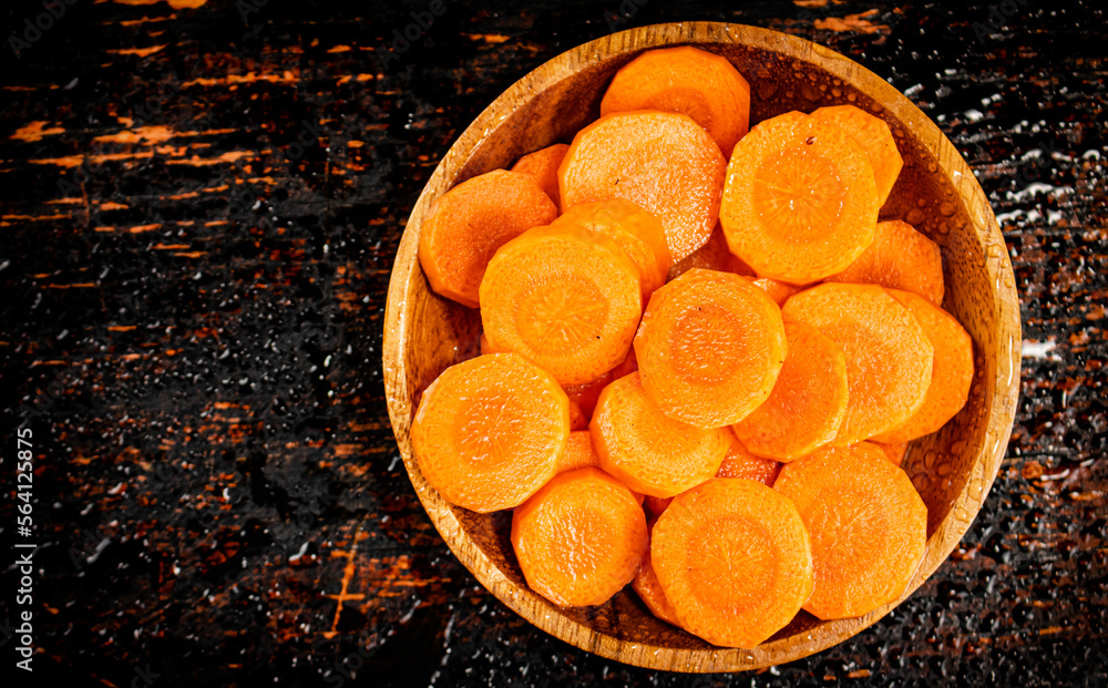 Wall mural Round pieces of fresh carrots on a wooden plate. 