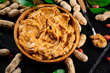Peanut butter on a stone board with peanuts in the shell. 