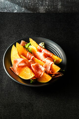 melon with parma on a dark background