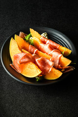 melon with parma on a dark background