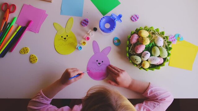 a little girl made an Easter egg out of paper and painted it with paints.