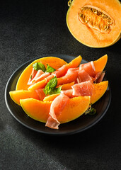 melon with parma on a dark background