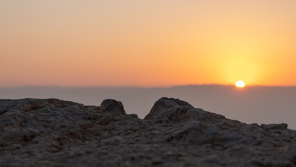 View  of rising sun over mountains of Jordan from ruins of the fortress wall of fortress of Masada...